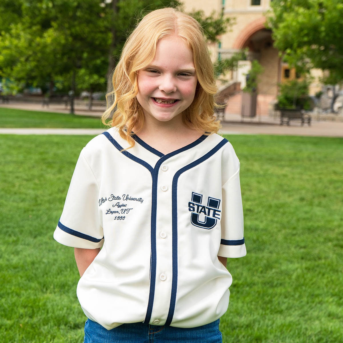 Young girl wearing utah state university baseball jersey in cream
